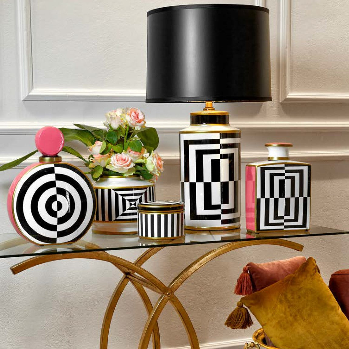 Колекция декоративни елементи Vogue в нежен розов цвят, с бели и черни ивици шахматно разположени. Различни форми и размери. Поставени върху консола с прочрачен стъклен плот и основа в златисто. 