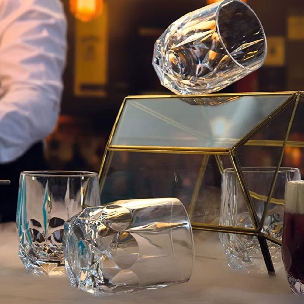 Кристална чаша в комплект от 6 бр. Alkemist DOF RCR Italy, много стилен и модерен модел. Поставени върху плот на бар - 2 изправени празни, 2 с наляти коктейли, 2 наклонени върху страничните гравирани форми. В дясно с лек дим от течния лед. Перфектен подарък за любители на уиски.