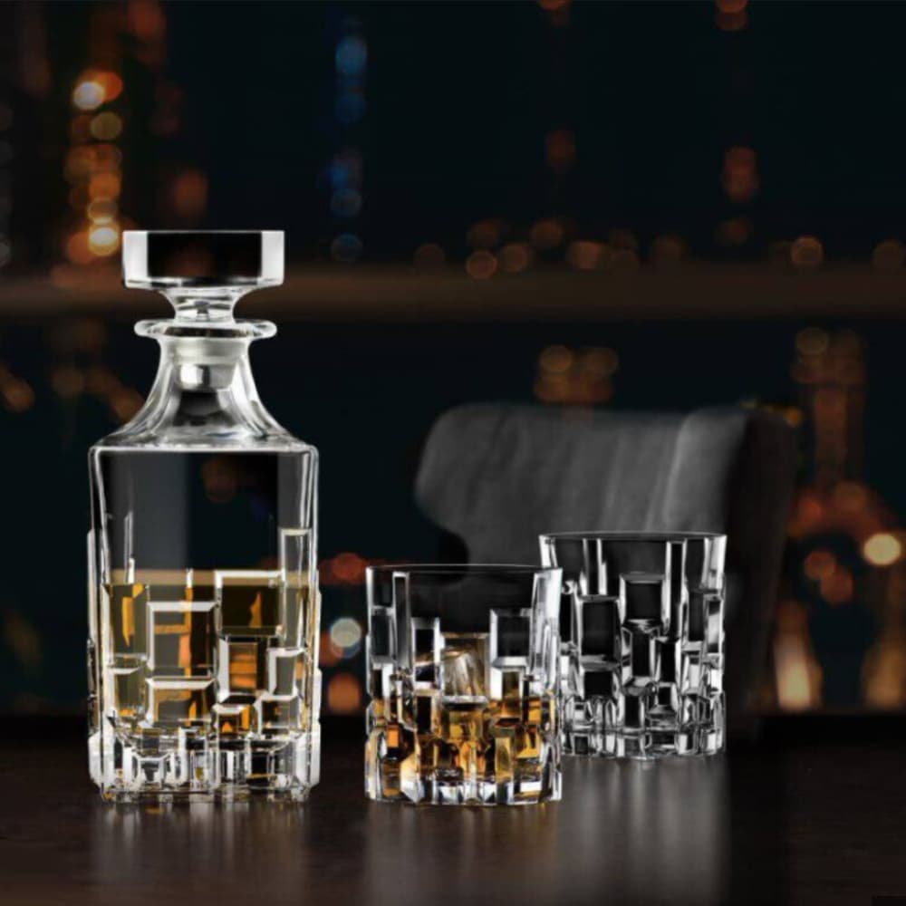 Eлегантна бутилка със уиски с две чаши за уиски, едната е празна, а другата е налята с уиски. Модел Etna. Поставени върху елегантна дървена маса тъмен махагон, с приглушена светлина с мрежа от лед светлини на задния фон, в елегантна бар обстановка.